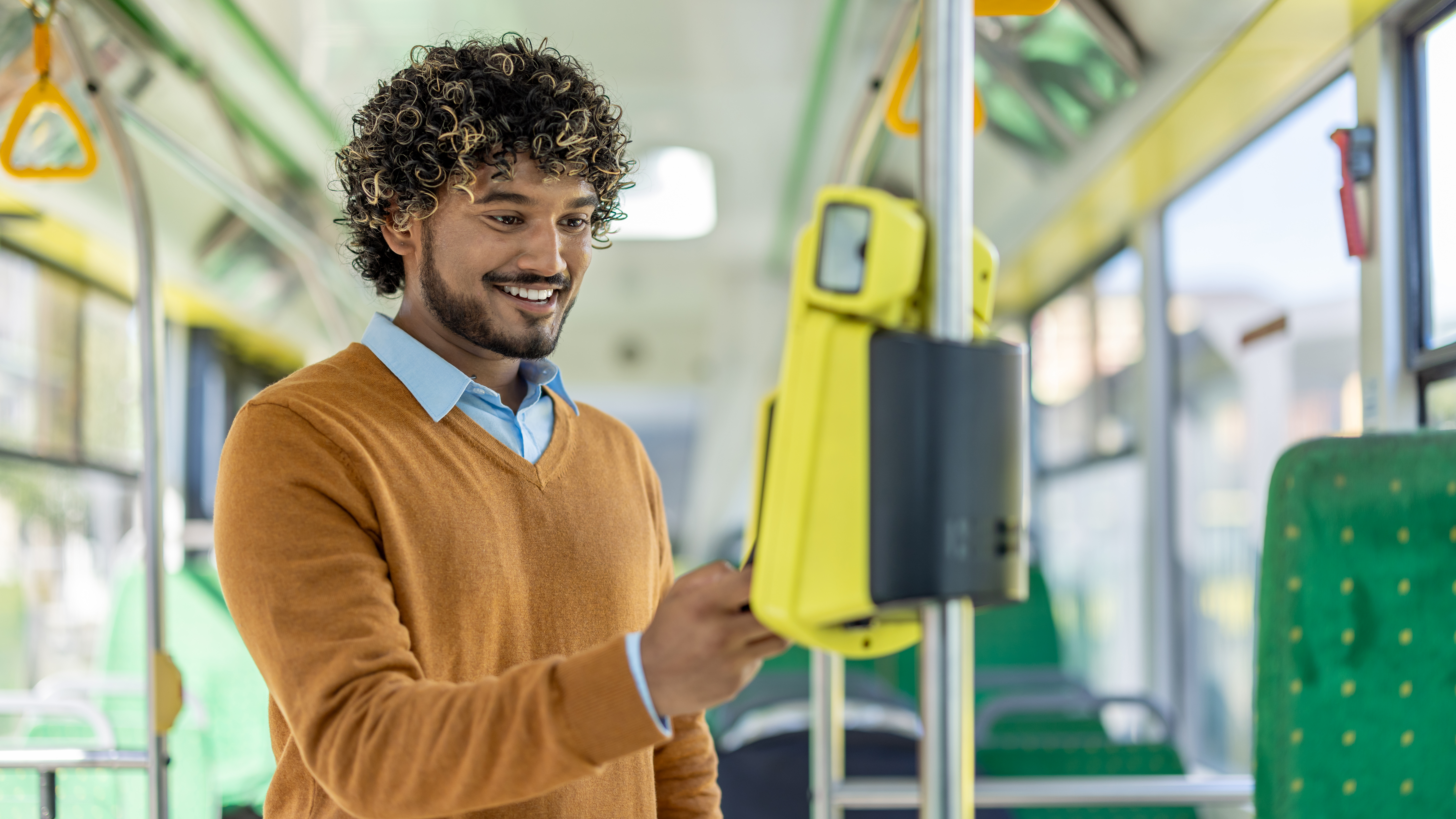 Person using a ticket validator on a public bus with green seats.