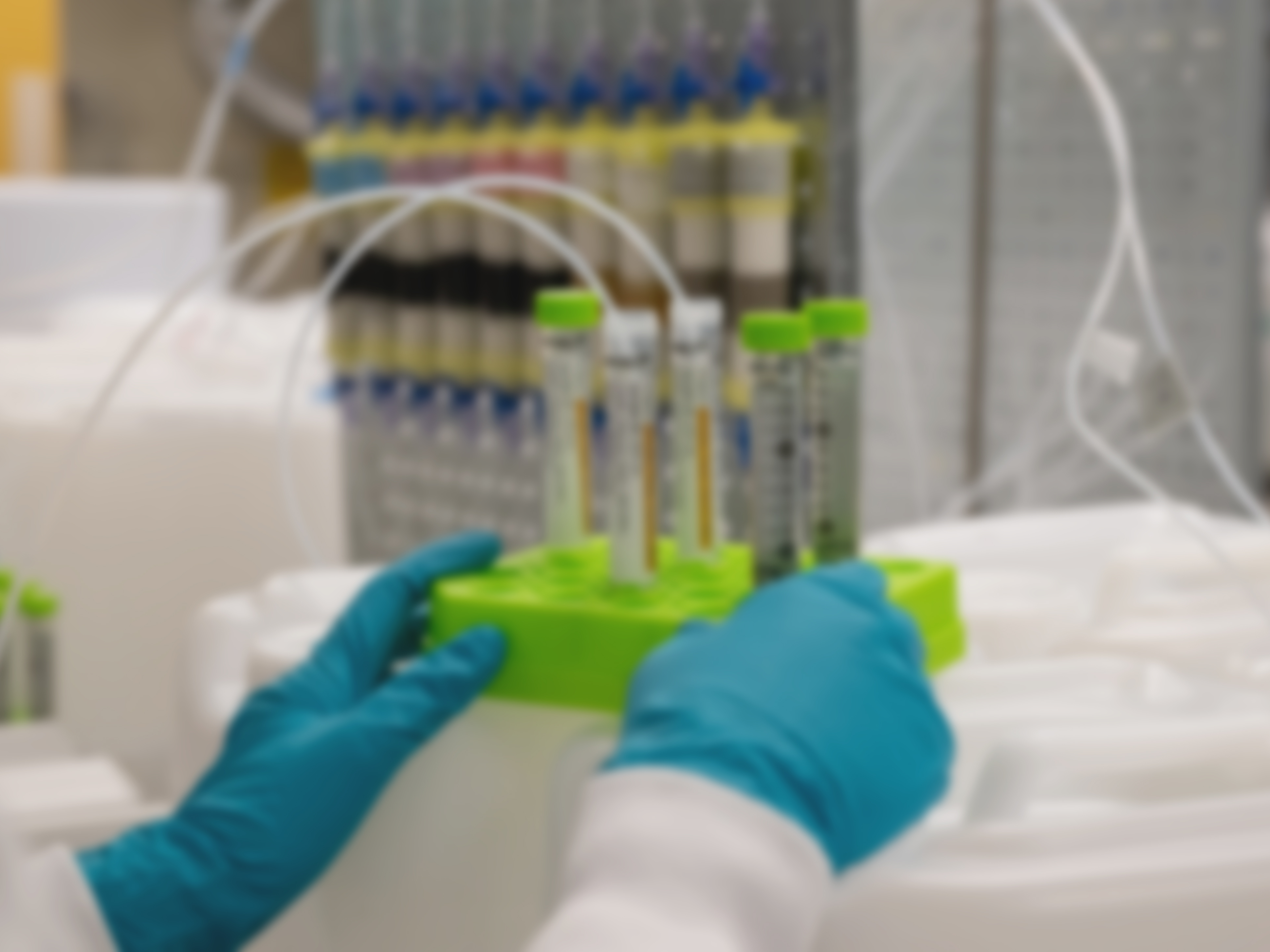 Gloved hands holding a test tube and pipette in a lab setting.