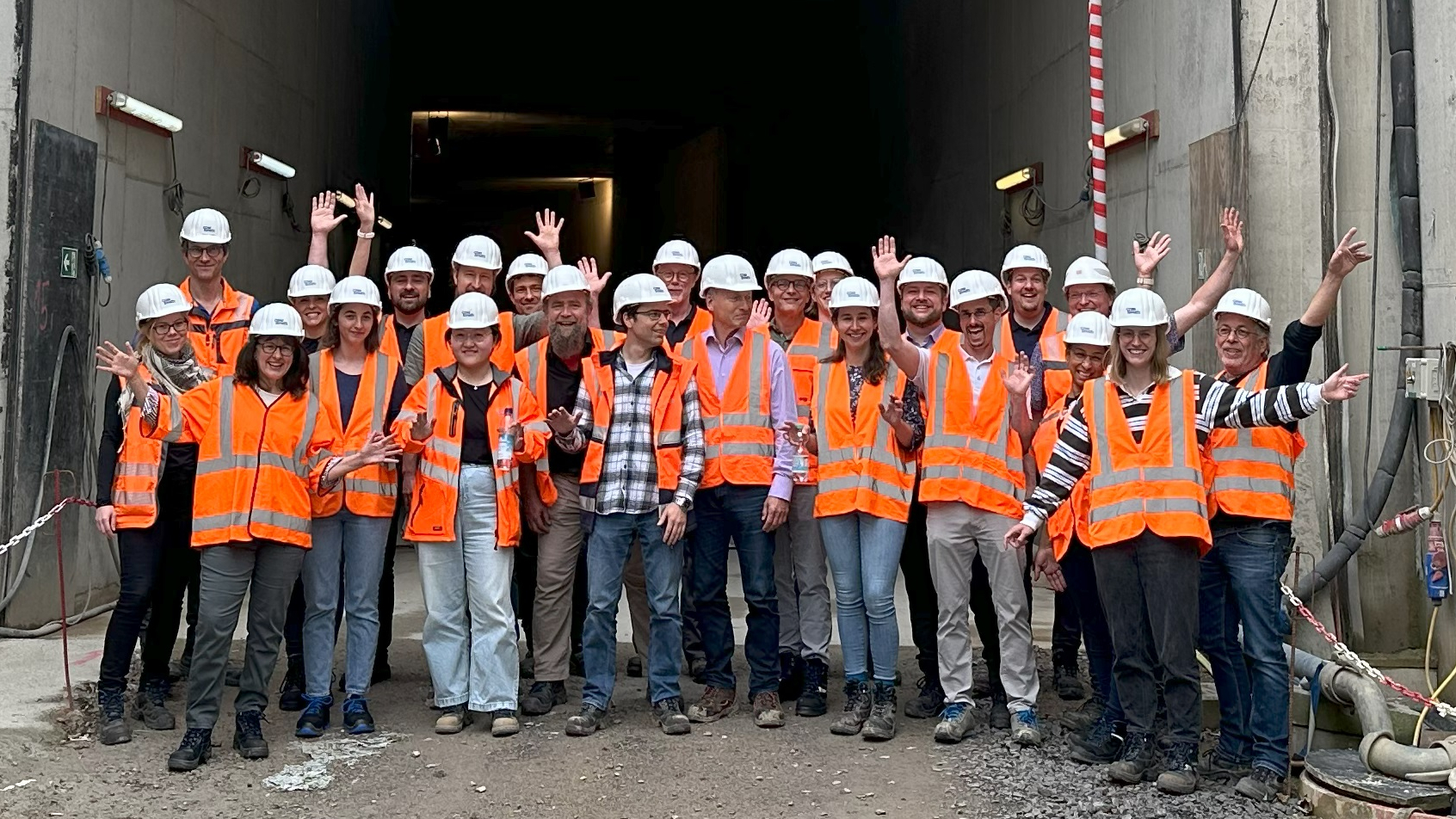 Group of construction workers in safety gear in front of a tunnel entrance.