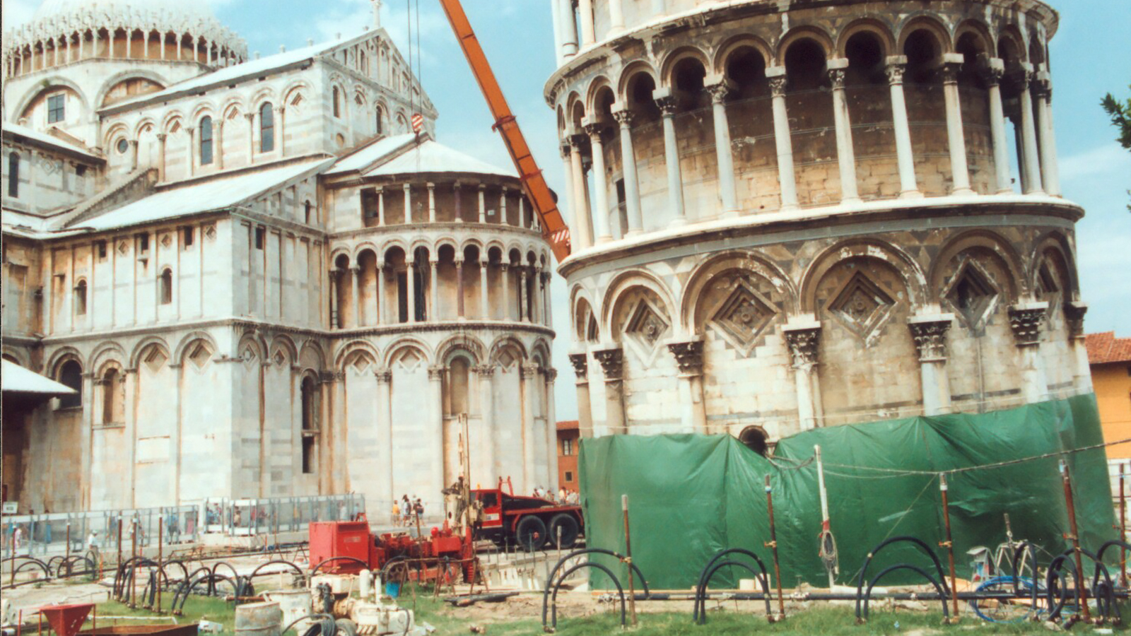 Leaning Tower of Pisa with surrounding construction site and crane.
