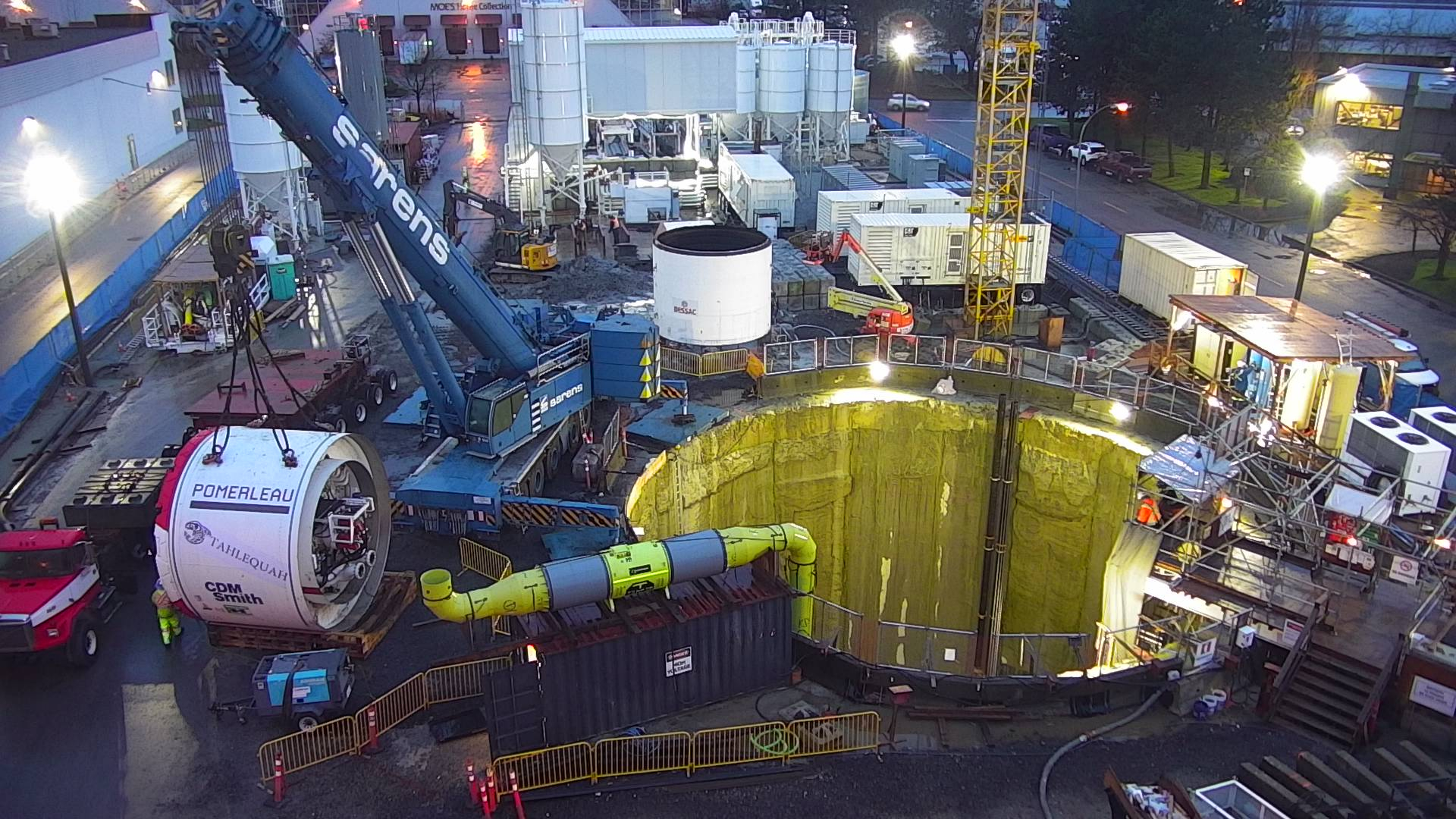 Construction site with crane, tunnel boring machine, and deep excavation pit.