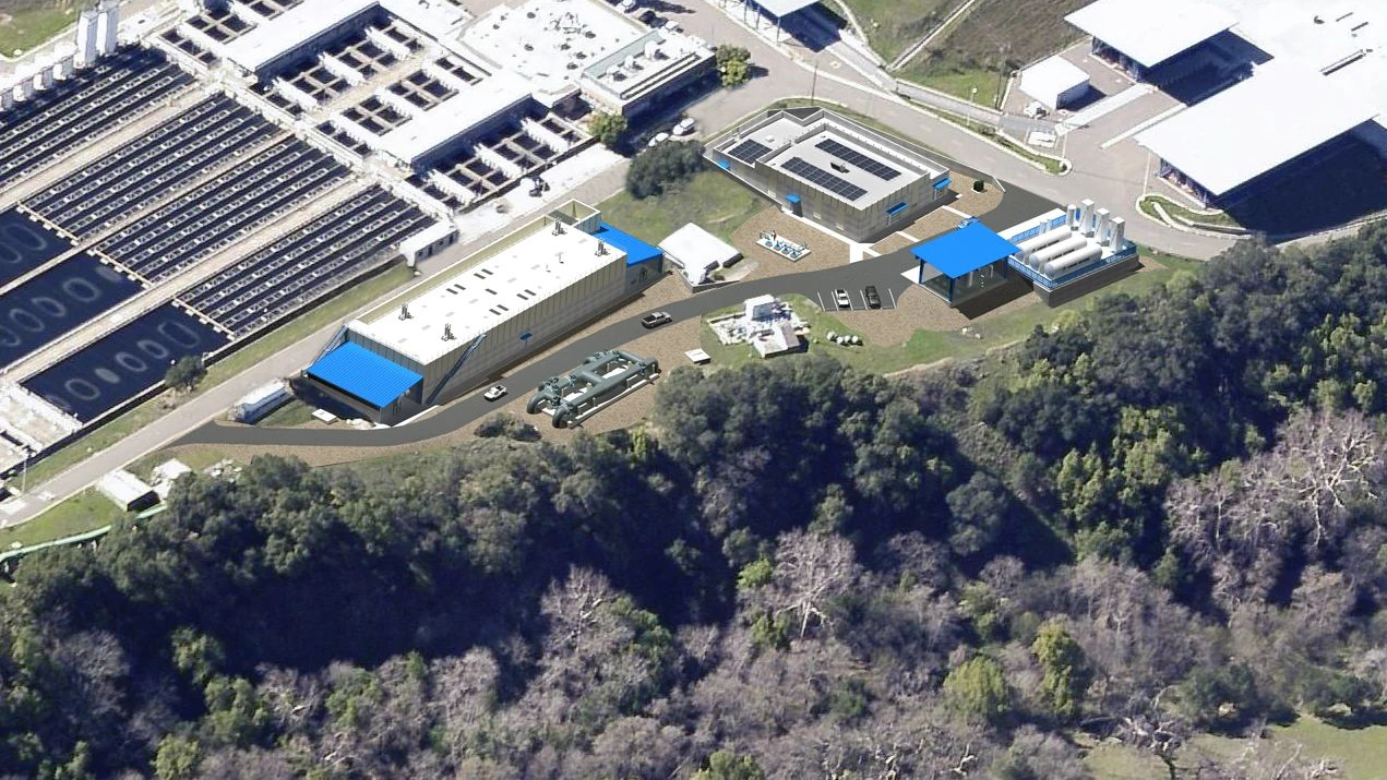 Aerial view of a water treatment plant with buildings and machinery, surrounded by trees.